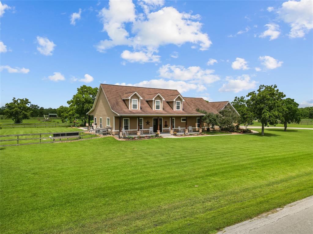 a view of a big house with a big yard and large trees