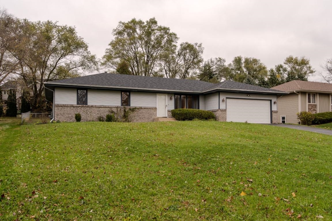 a front view of house with yard and trees in the background