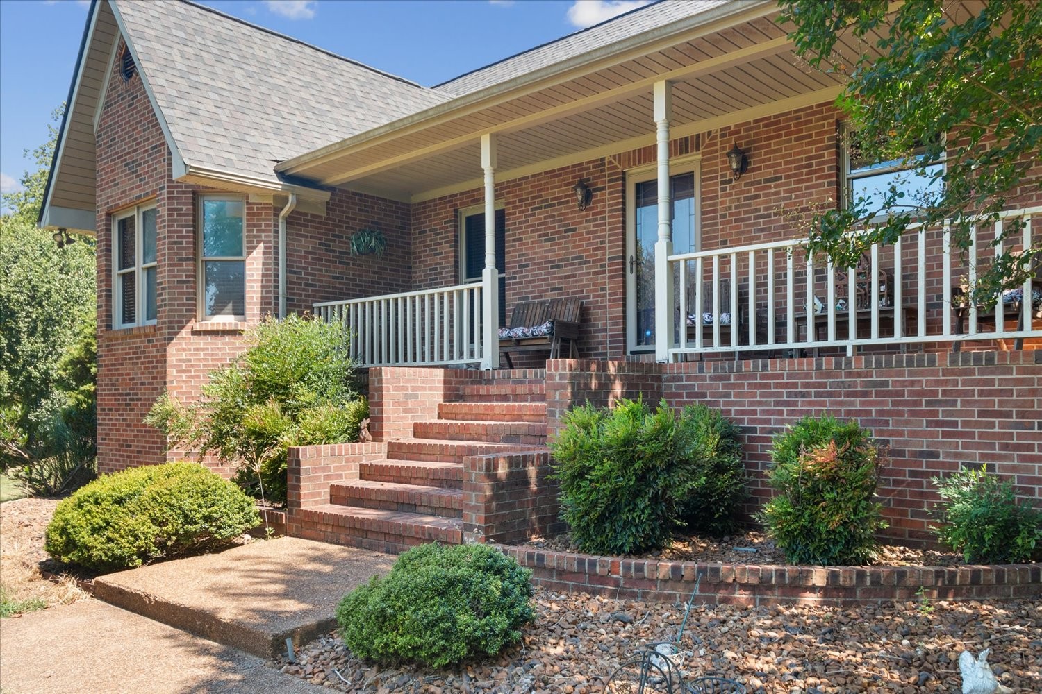 a view of a house with brick walls plants and large trees