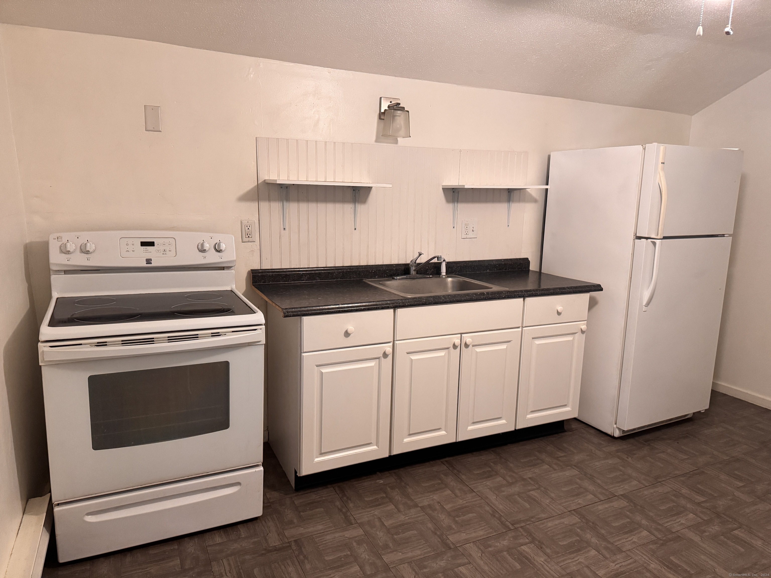 a kitchen with granite countertop white cabinets and white appliances