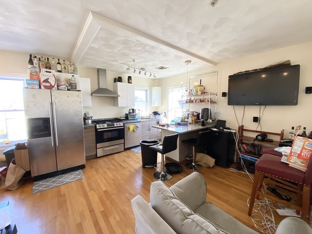 a living room with stainless steel appliances furniture and a flat screen tv