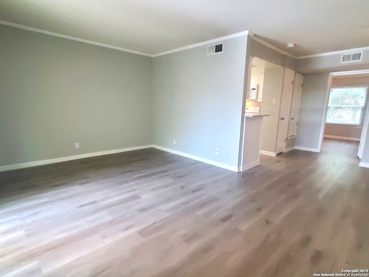 a view of empty room with wooden floor and fan