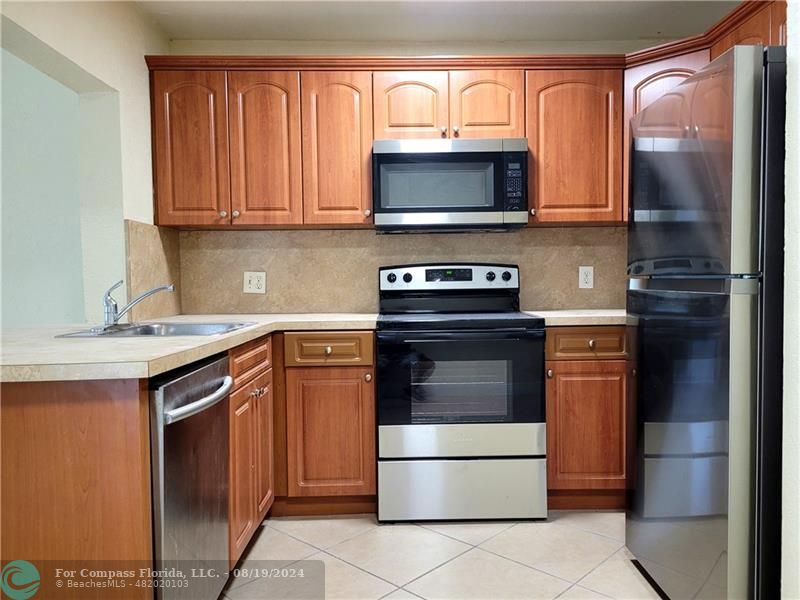 a kitchen with stainless steel appliances granite countertop a refrigerator stove and sink