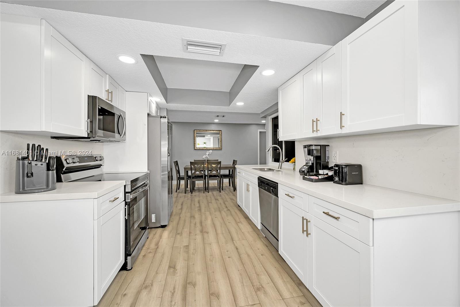 a kitchen with granite countertop a sink a counter top space stainless steel appliances and cabinets