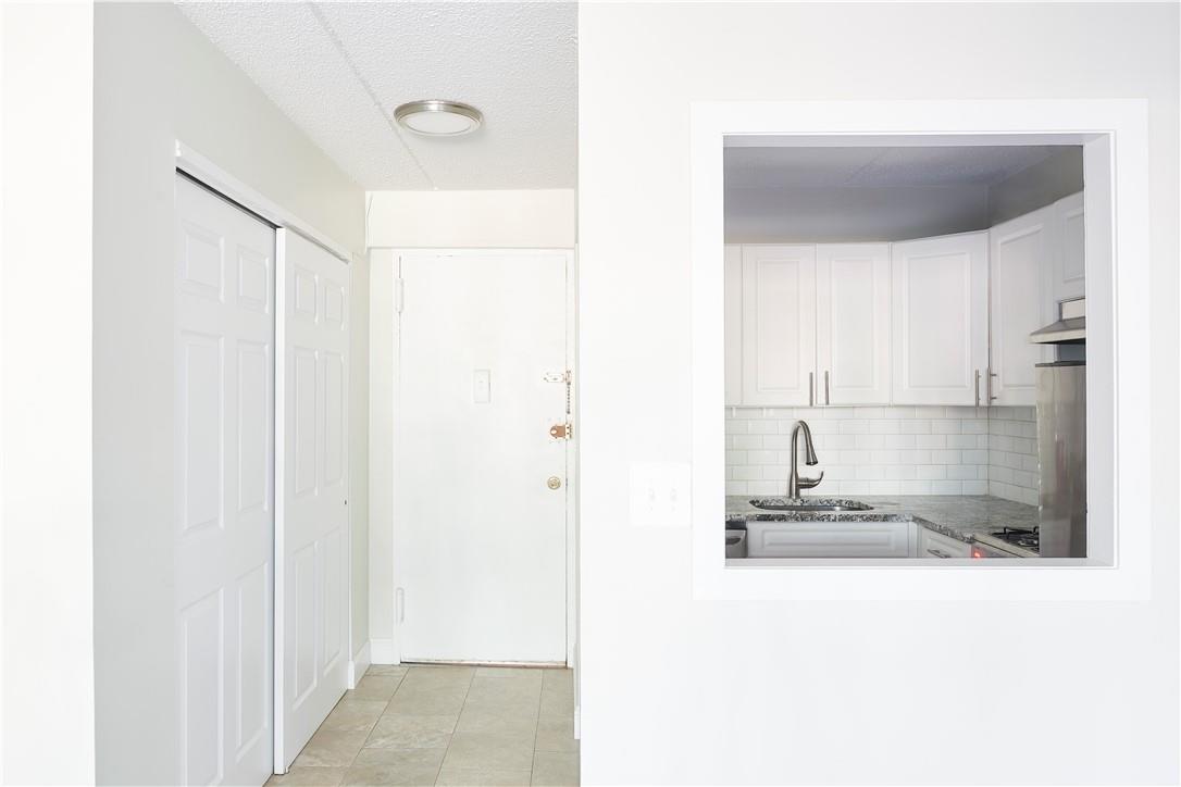 White cabinets, backsplash, light tile patterned floors, a textured ceiling.