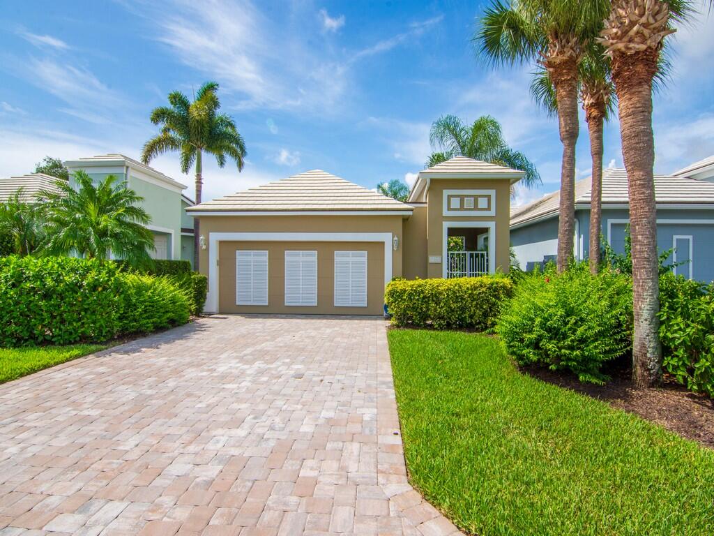 a front view of a house with a garden and palm trees