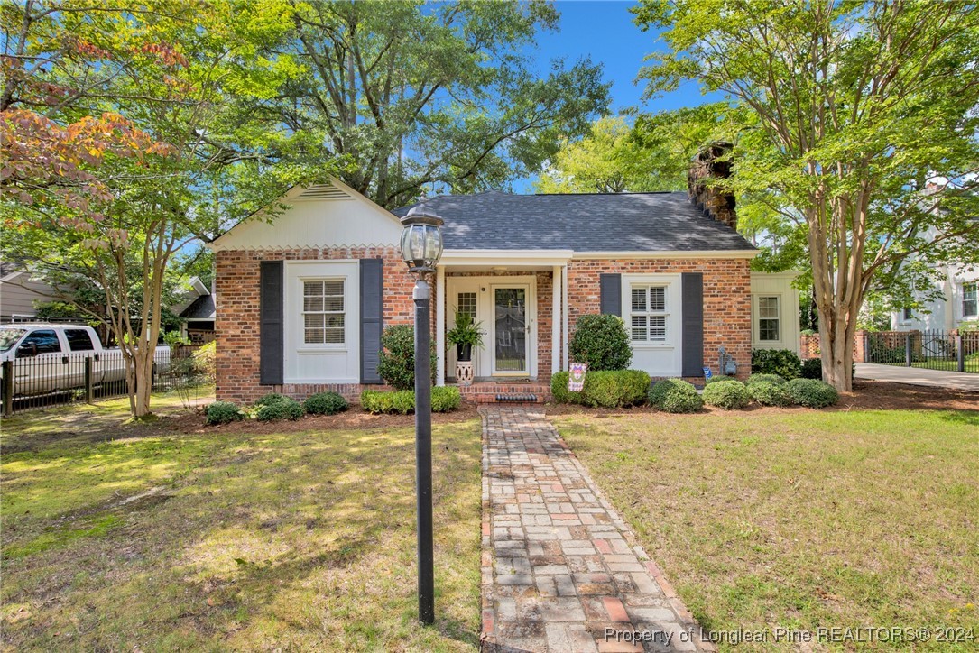 a front view of a house with a garden and tree