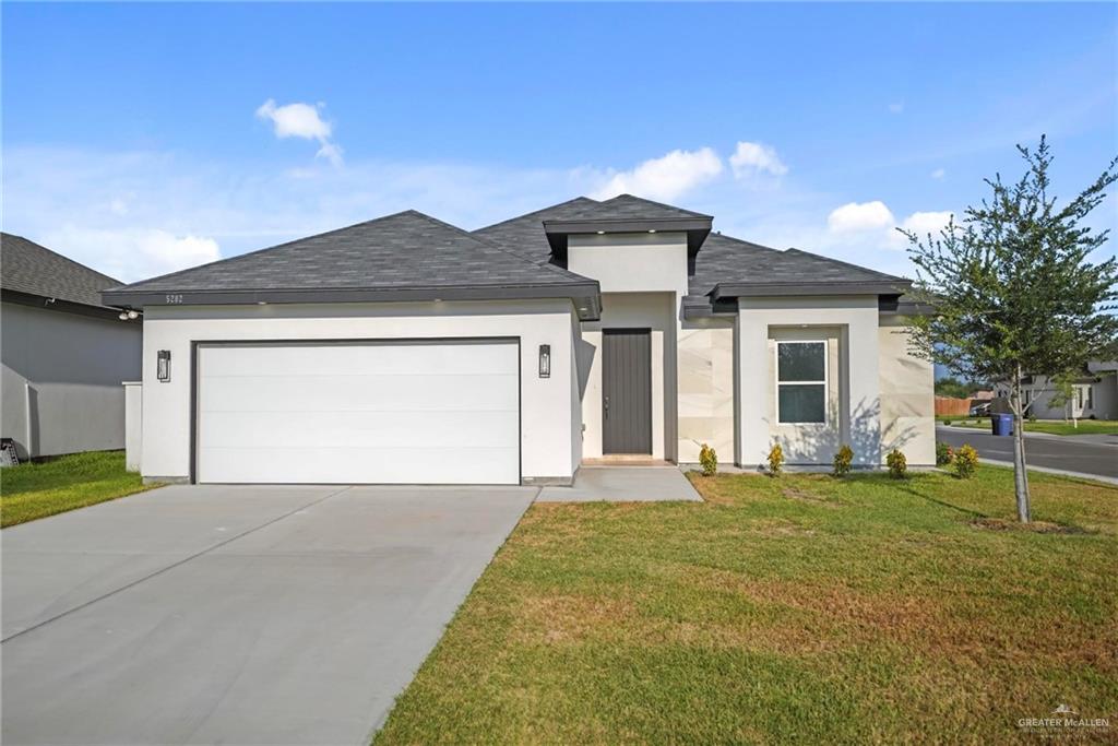 View of front of home featuring a front lawn and a garage