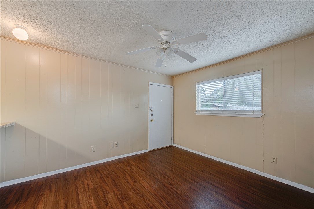 an empty room with wooden floor fan and windows