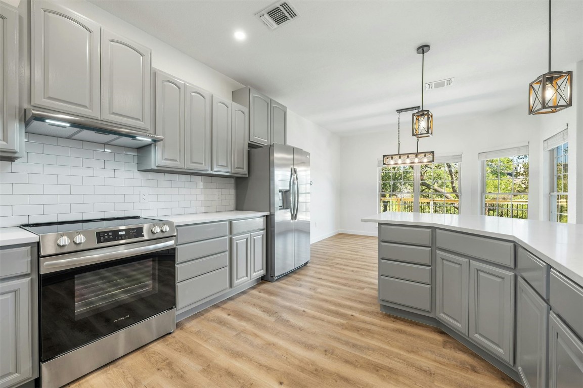 a kitchen with stainless steel appliances granite countertop a stove a sink and a refrigerator