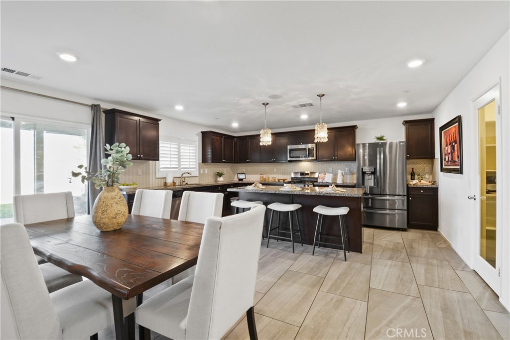 a kitchen with a dining table chairs and refrigerator