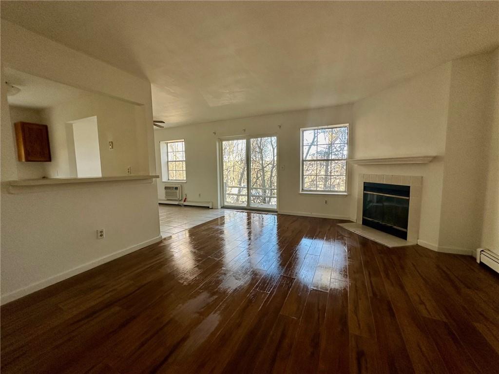 Unfurnished living room featuring hardwood / wood-style floors, a tiled fireplace, and plenty of natural light