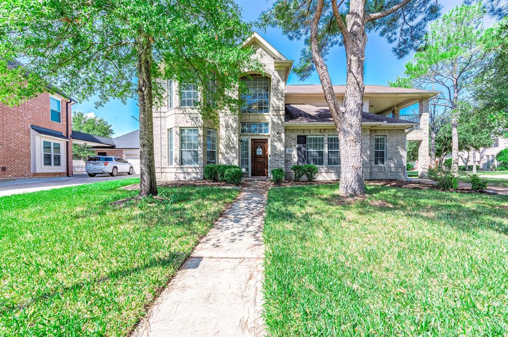 Beautiful front exterior with porte cochere on the right of the home and covered balcony above.