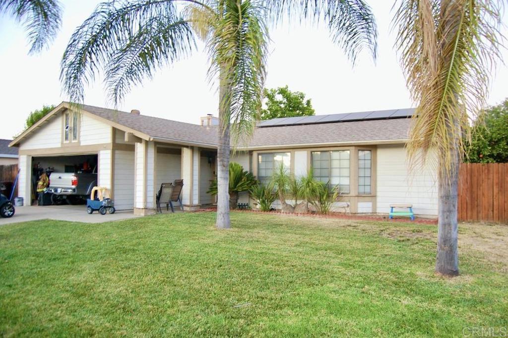 a view of a house with a yard and palm trees