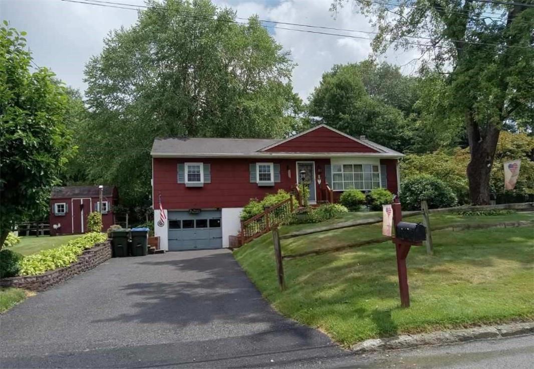 Ranch-style house featuring a garage, a storage shed, and a front yard