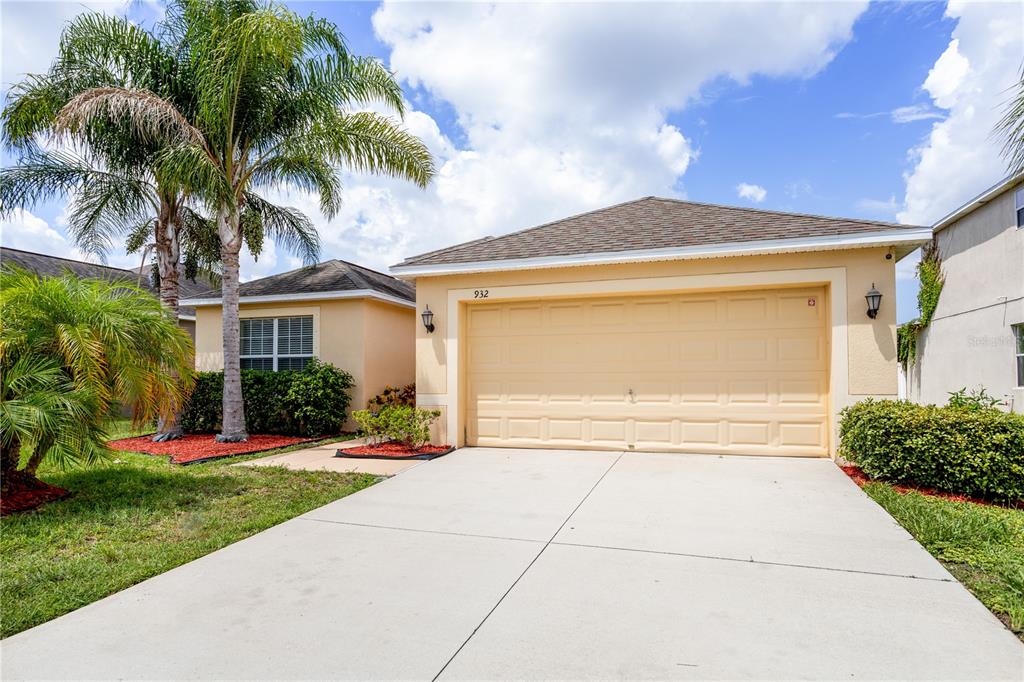 a view of a house with a yard and palm trees