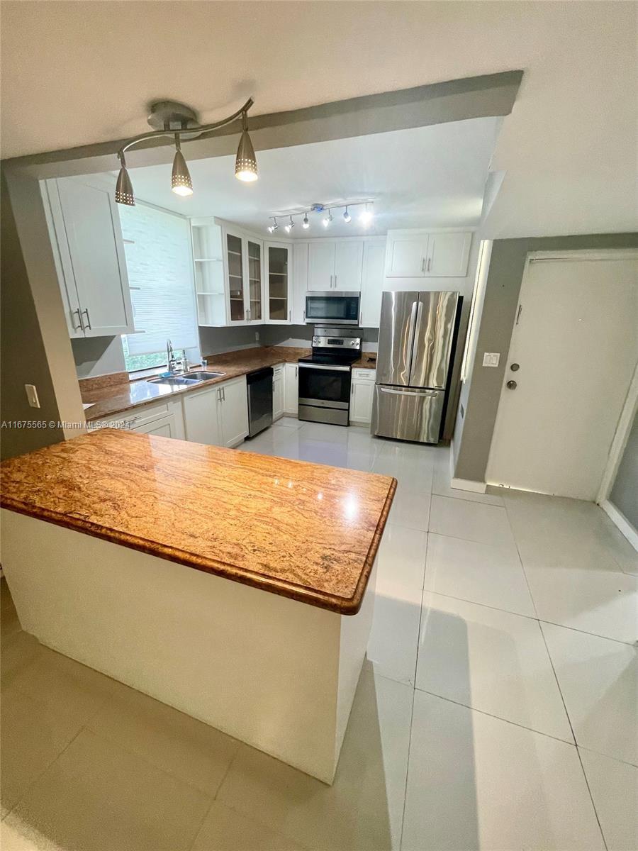 a large kitchen with stainless steel appliances granite countertop a sink and cabinets