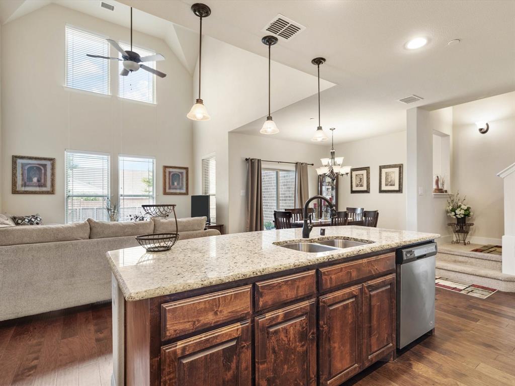 a dining hall with stainless steel appliances granite countertop a sink a stove and a wooden floors