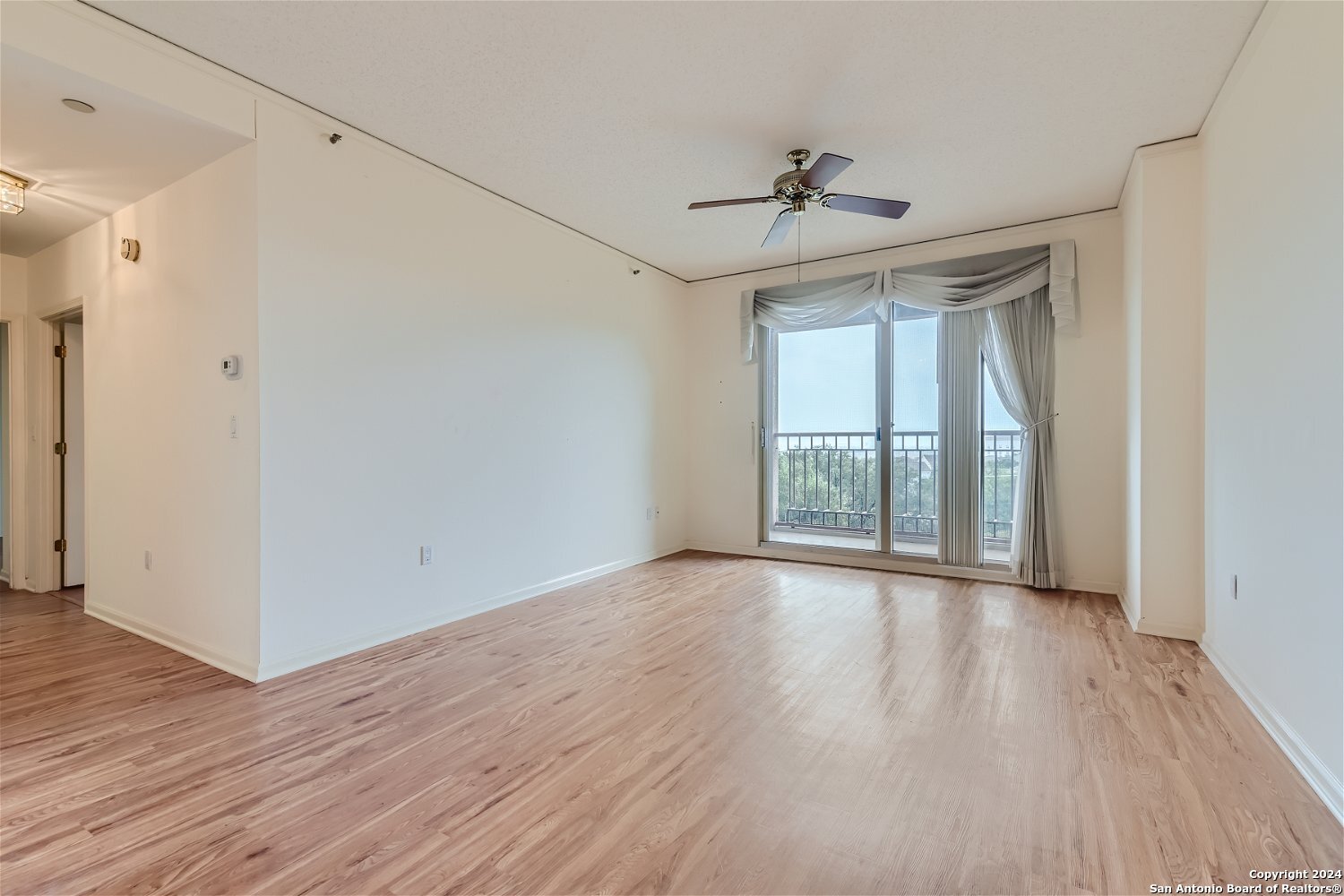 a view of an empty room with wooden floor fireplace and a window