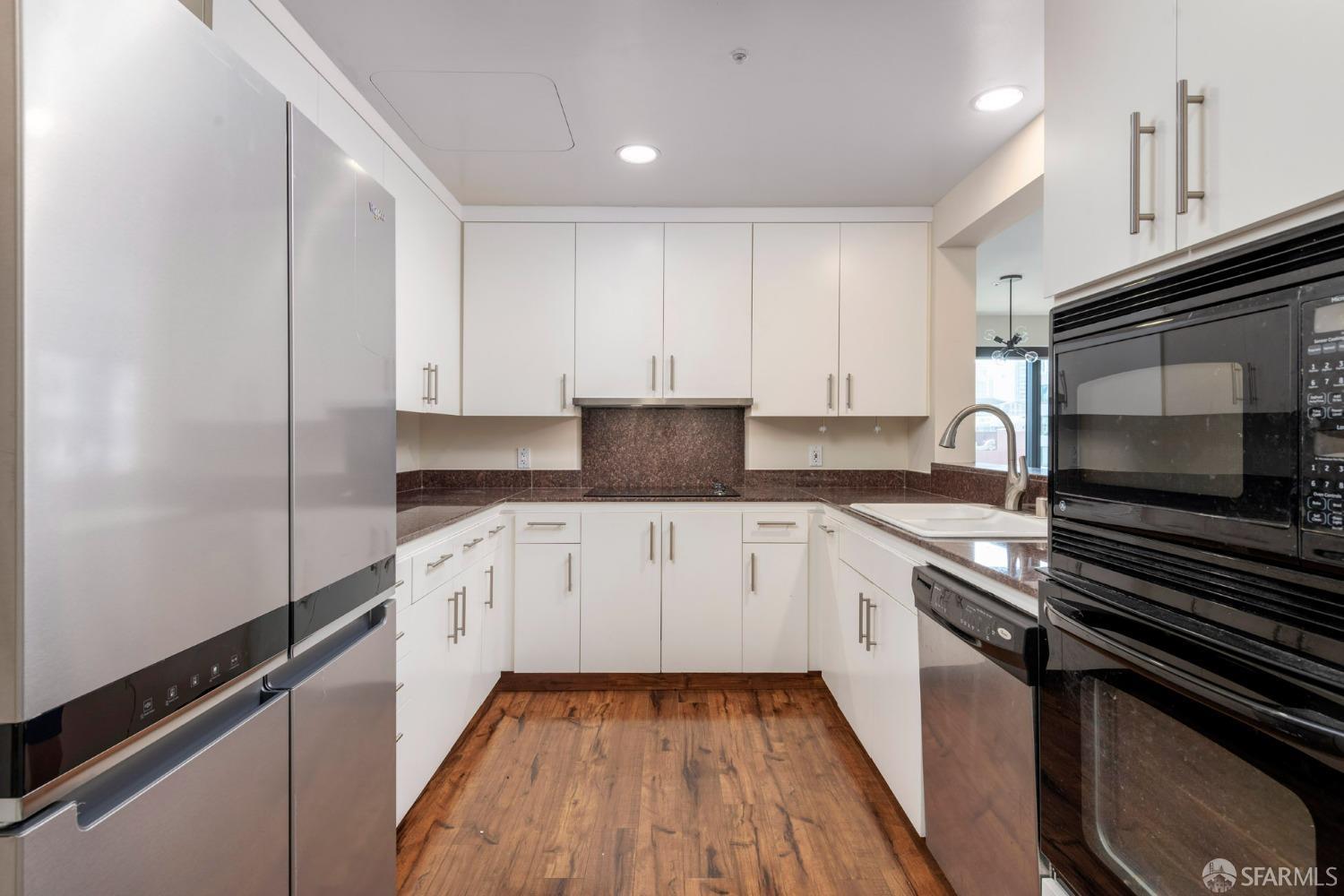 a kitchen with granite countertop white cabinets and stainless steel appliances