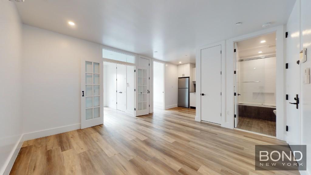 a view of a hallway with wooden floor and a bathroom