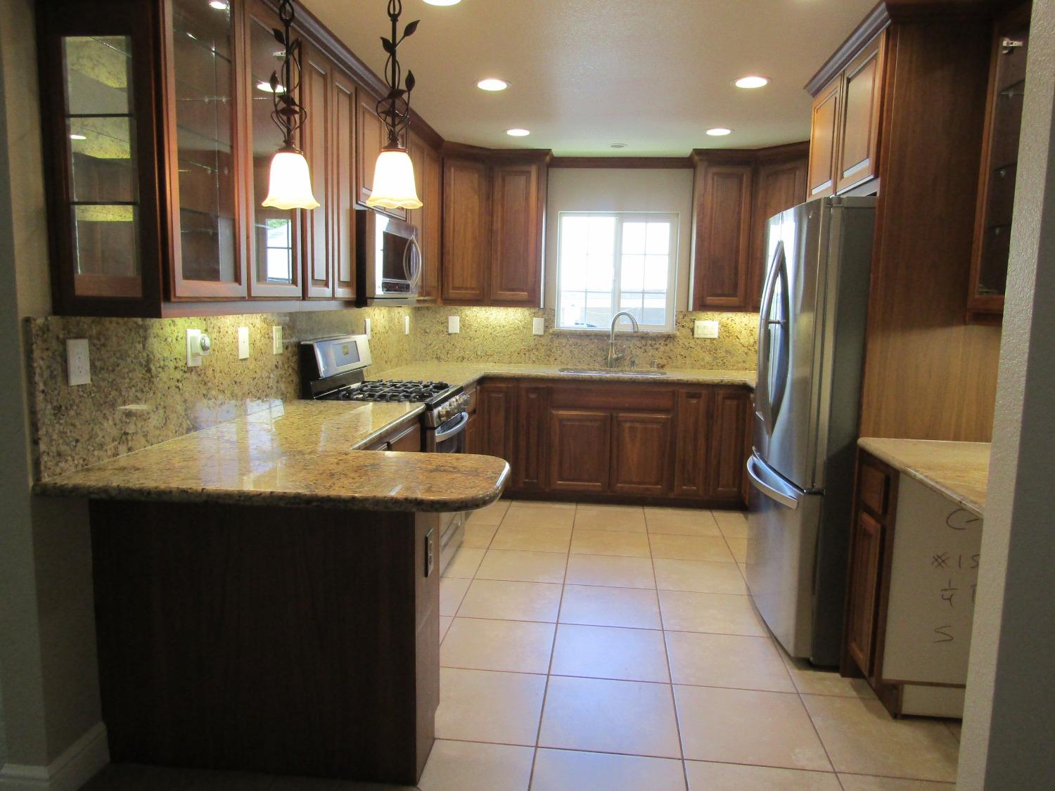 a kitchen with stainless steel appliances granite countertop a sink counter space and a refrigerator