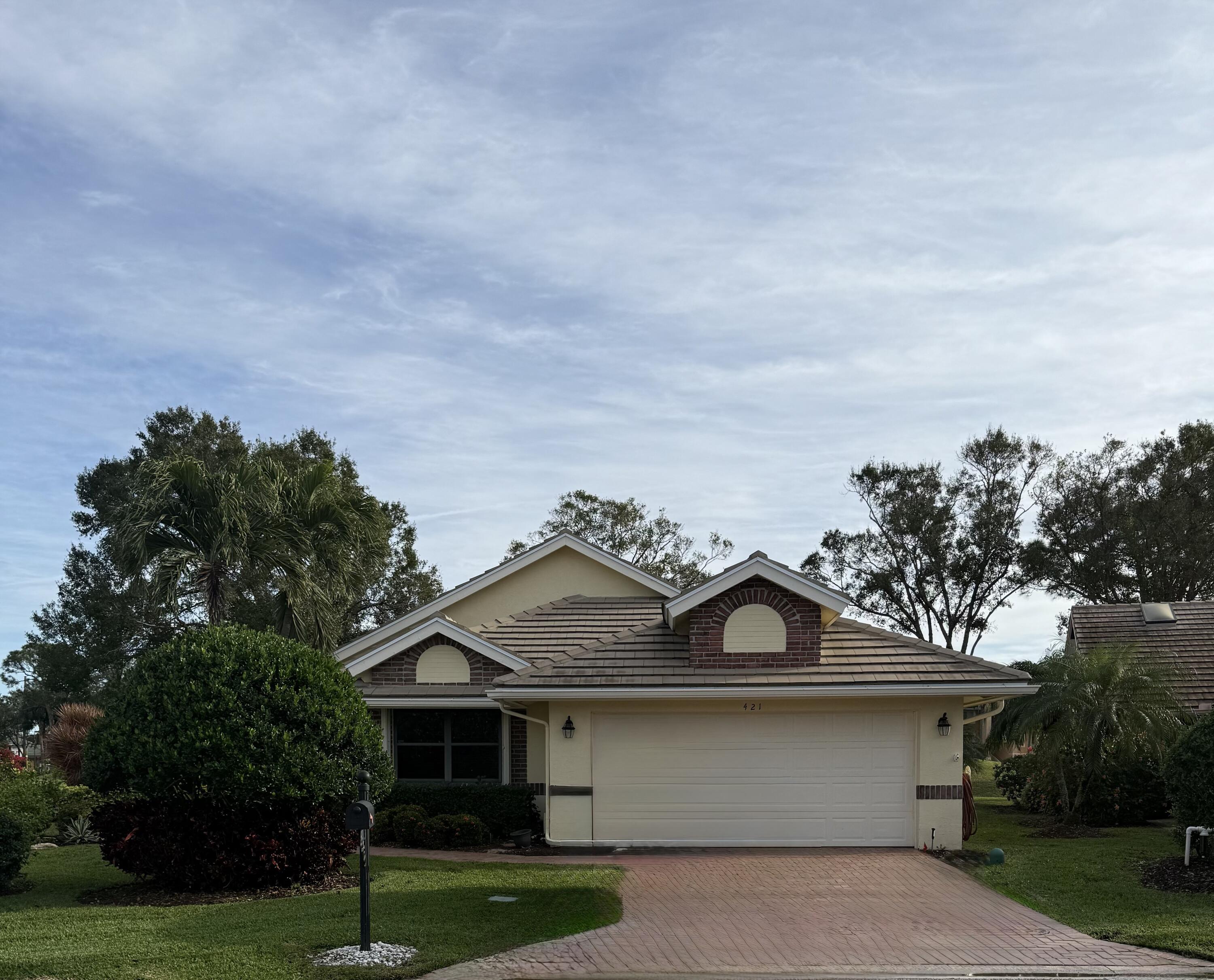 a front view of a house with a garden and trees