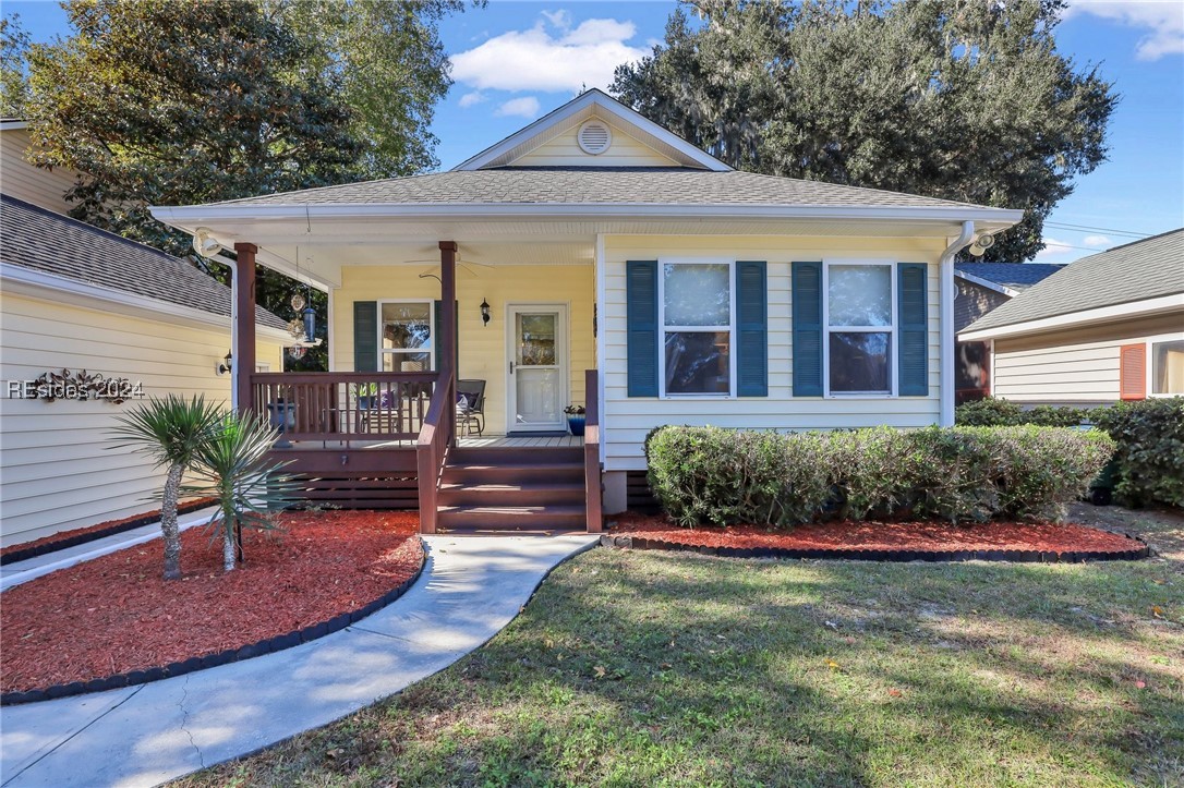 Bungalow with ceiling fan, a front lawn, and a por