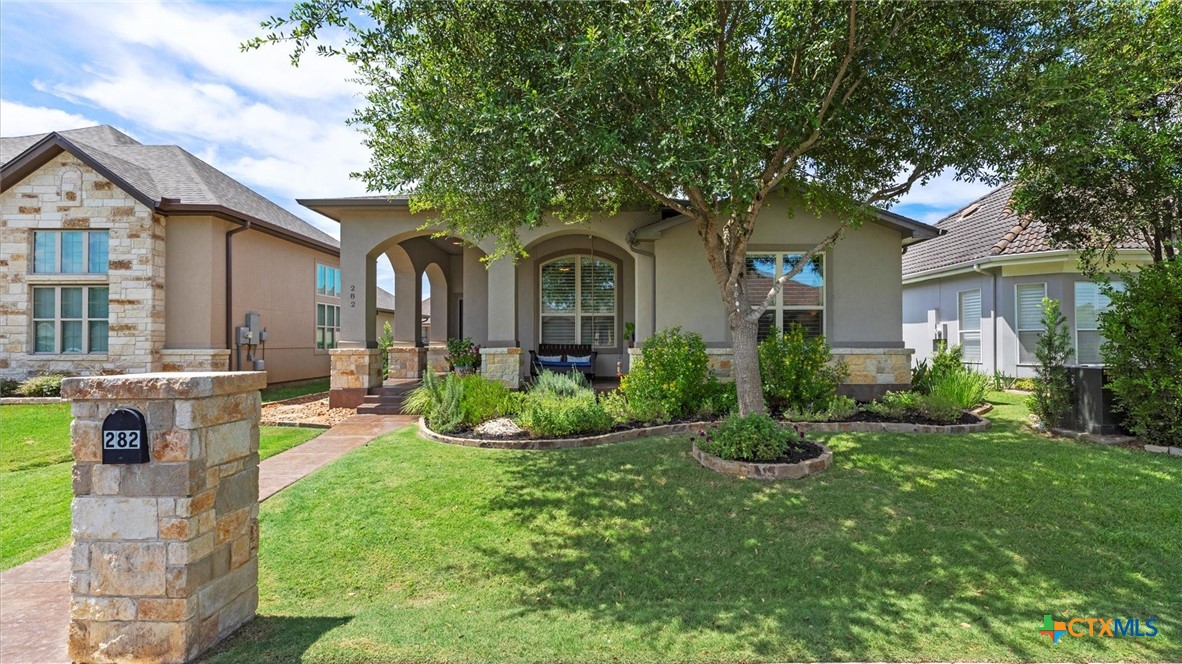 a front view of a house with garden and trees