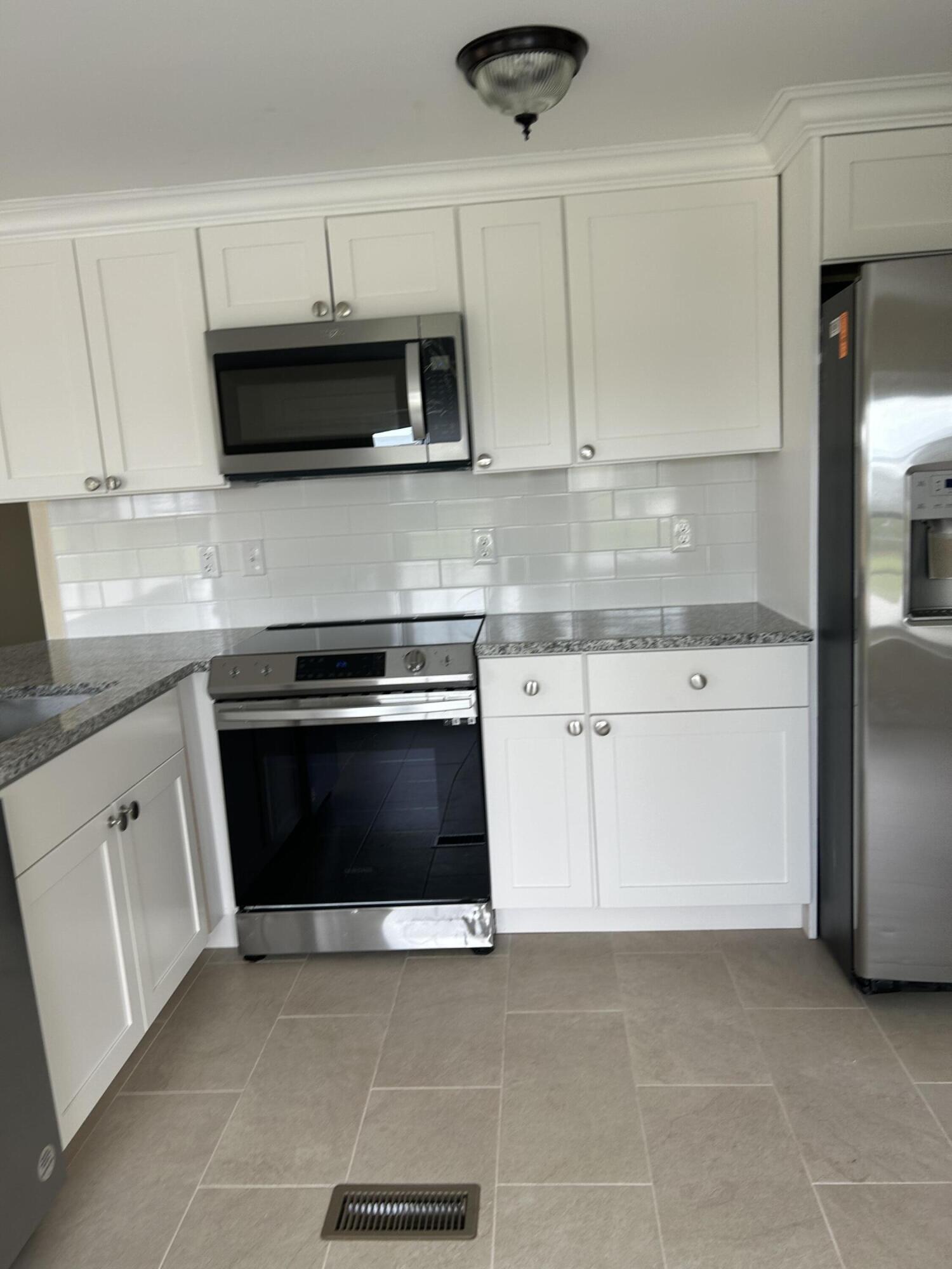 a kitchen with white cabinets and stainless steel appliances