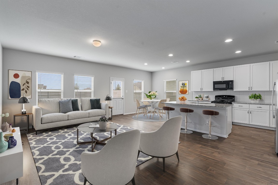 a living room with furniture white walls and kitchen view