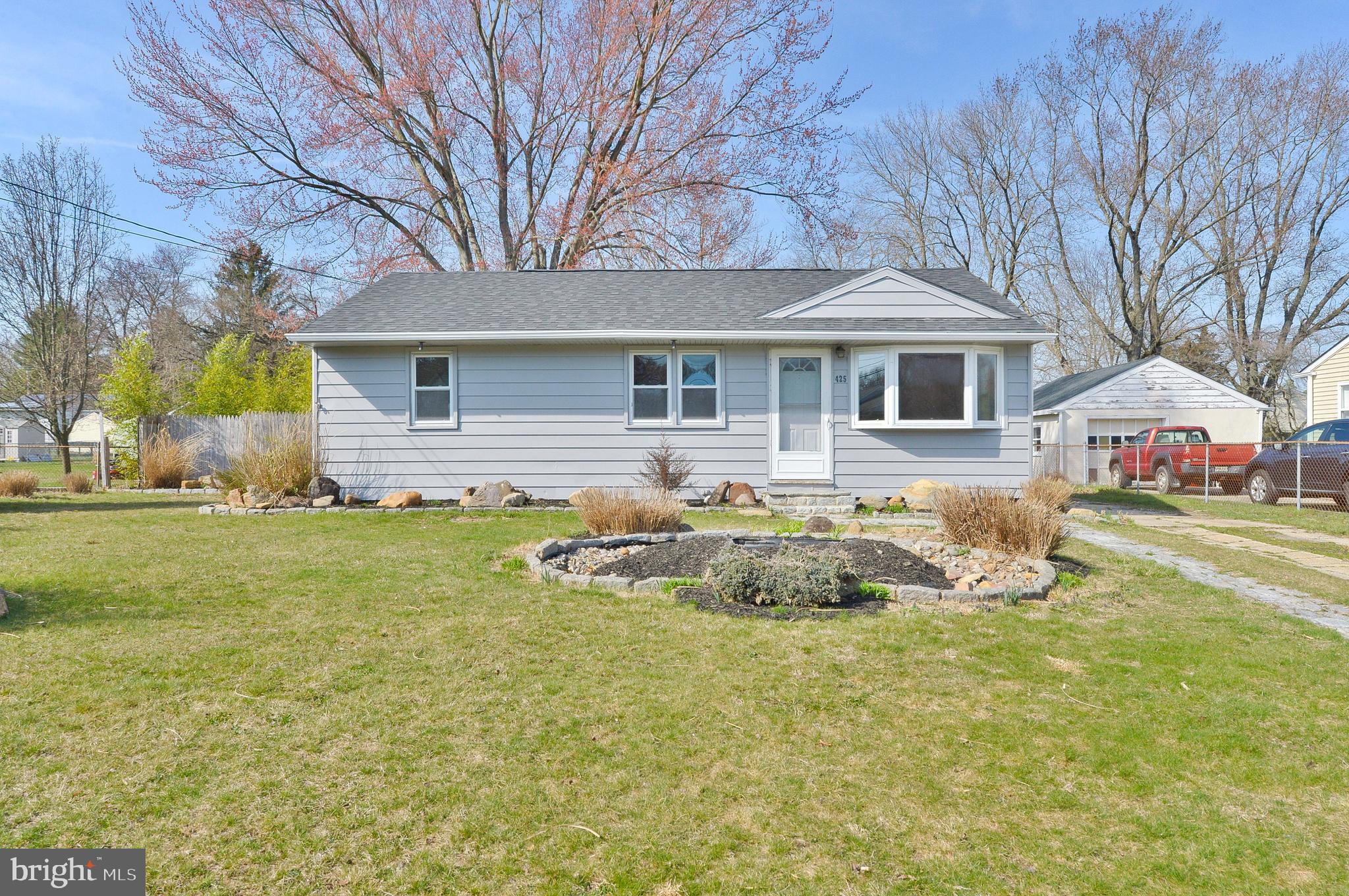 a front view of house with yard and trees in the background