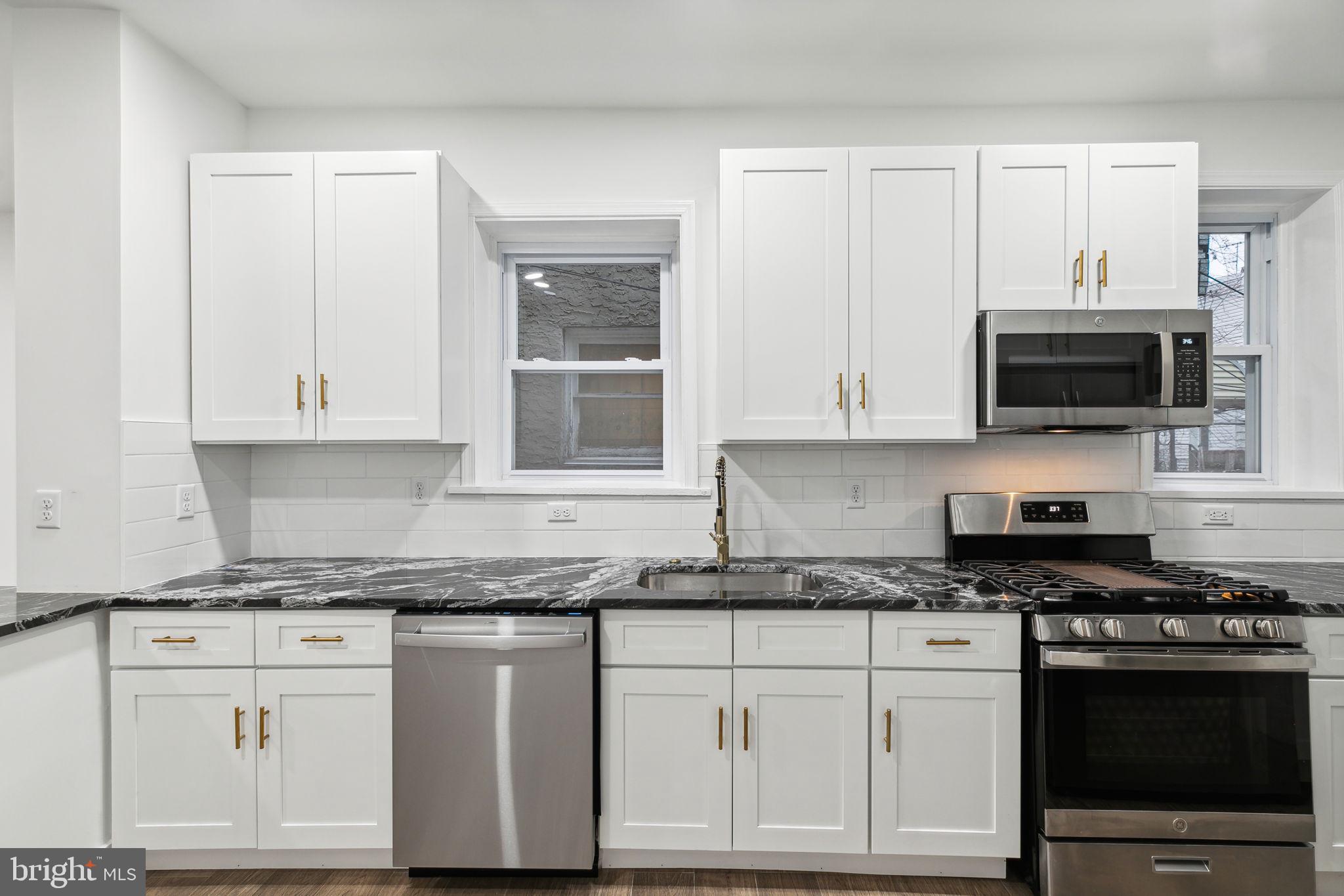 a kitchen with granite countertop white cabinets and stainless steel appliances