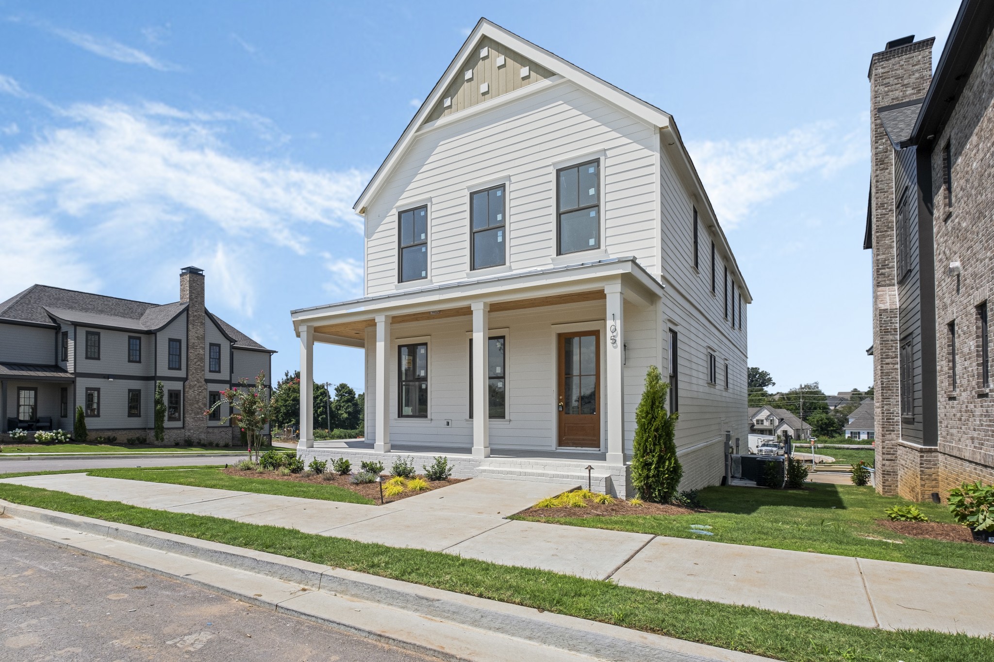 a view of a white house with a yard and plants next to a road