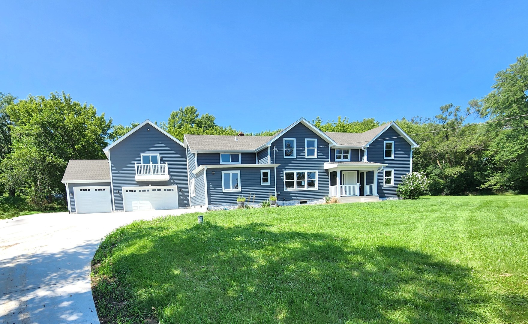 a front view of a house with a yard and large trees