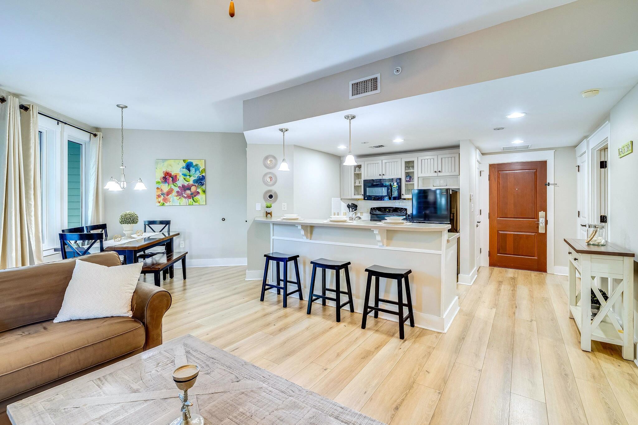 a living room kitchen with stainless steel appliances furniture a dining table and kitchen view