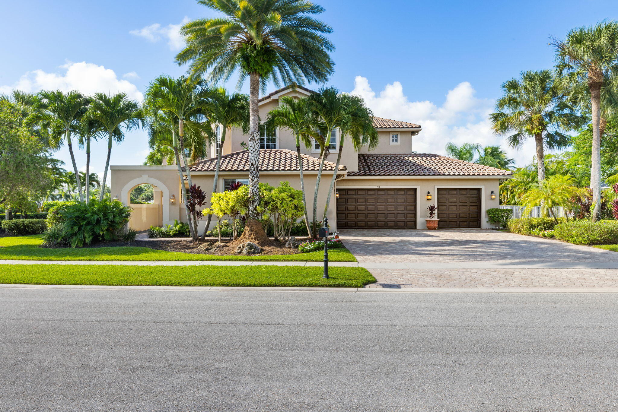 a front view of house with small garden and palm trees