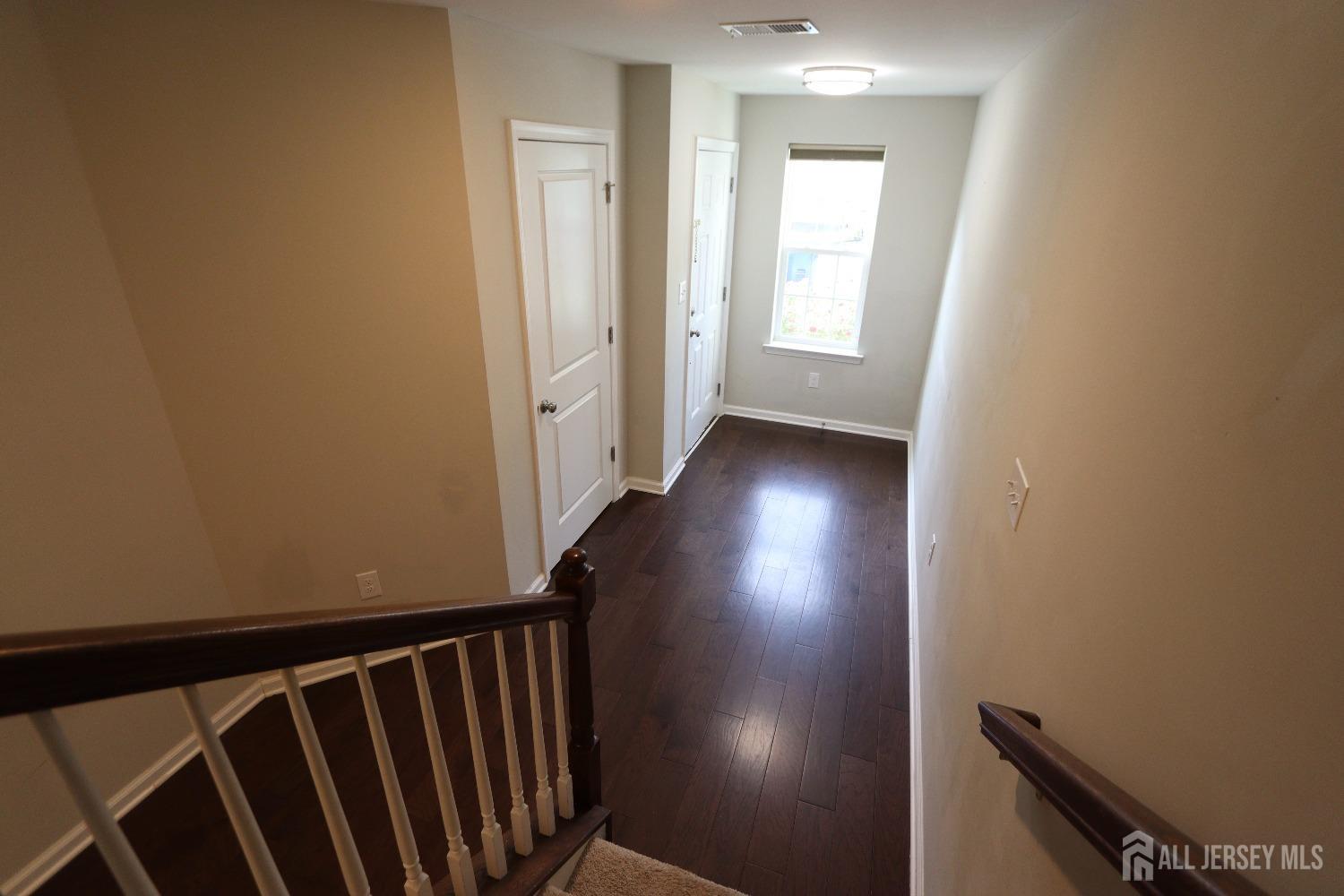 a view of a hallway with wooden floor and staircase