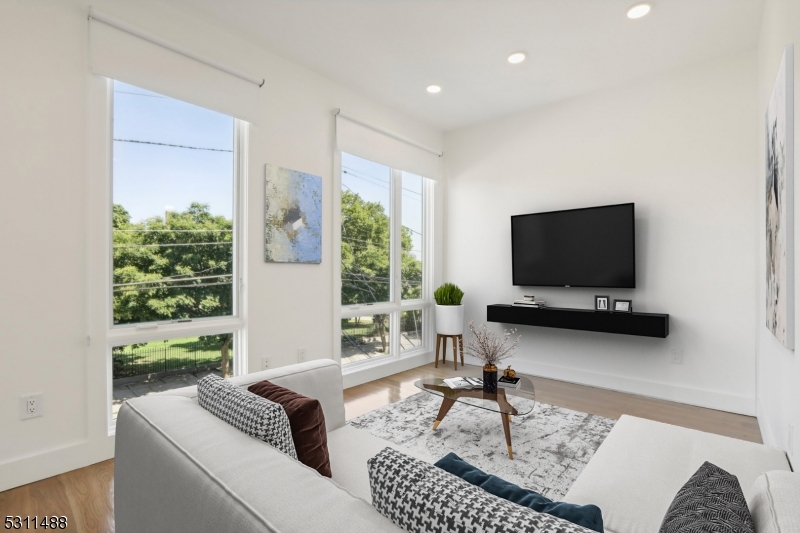 a living room with furniture a flat screen tv and a large window