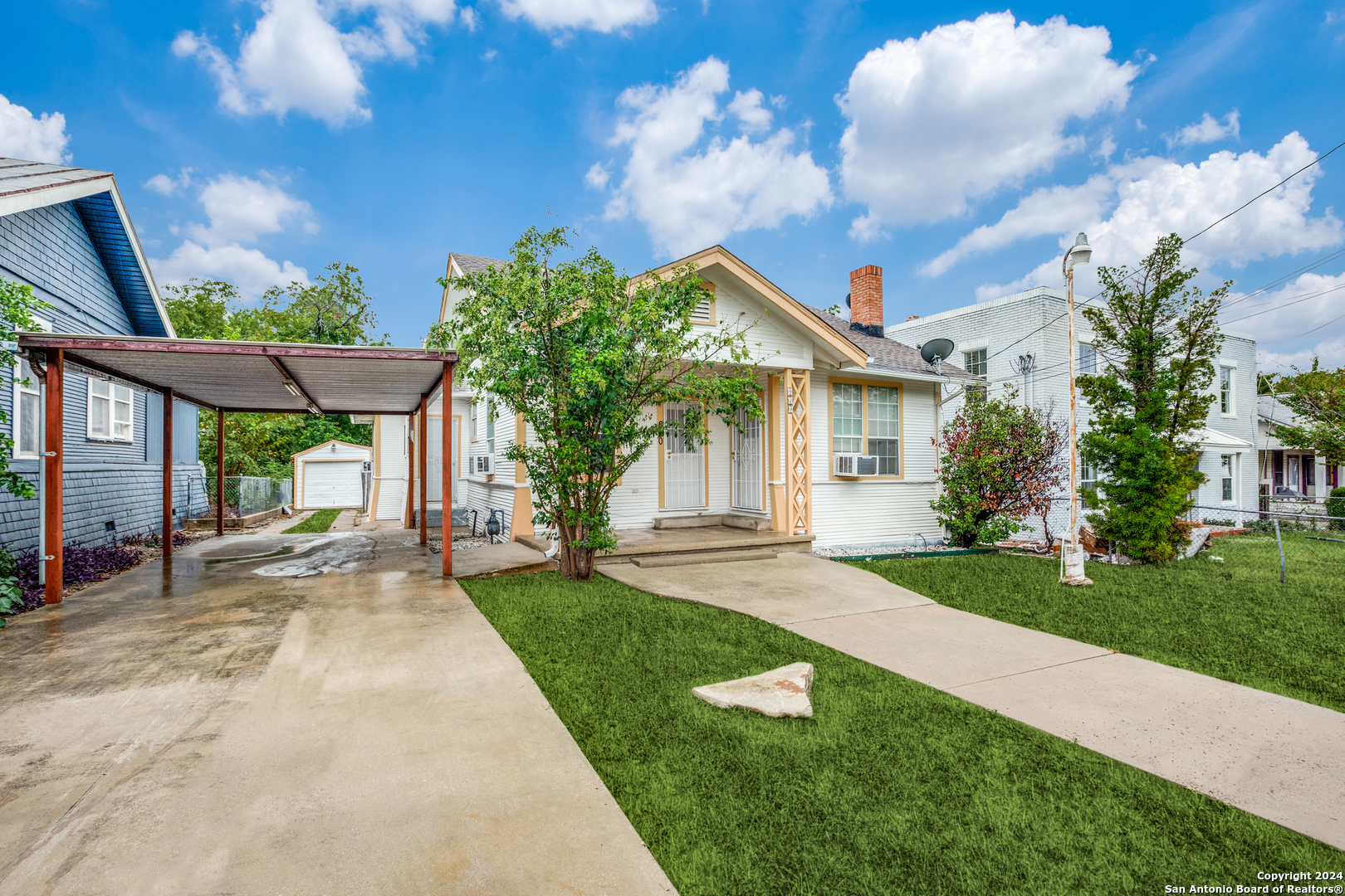 a view of a house with brick walls plants and large tree