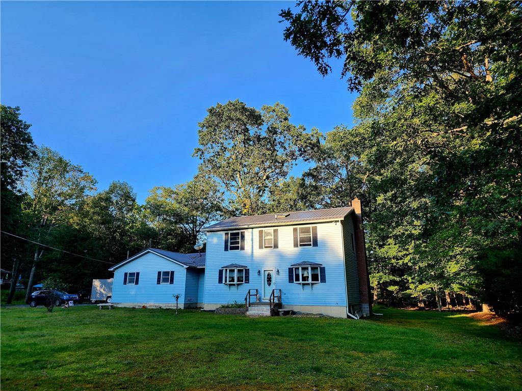 a view of house with yard and trees in the background