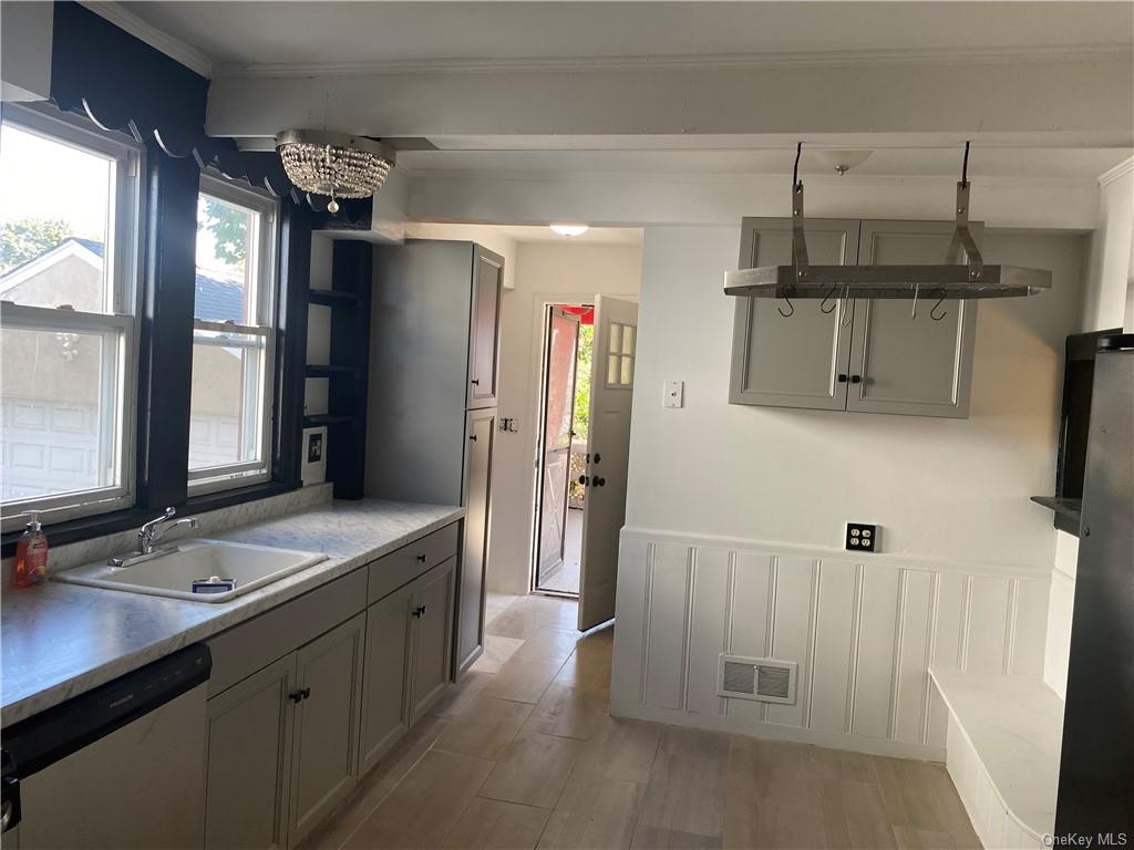 Kitchen featuring pendant lighting, light wood-type flooring, dishwasher, sink, and gray cabinetry