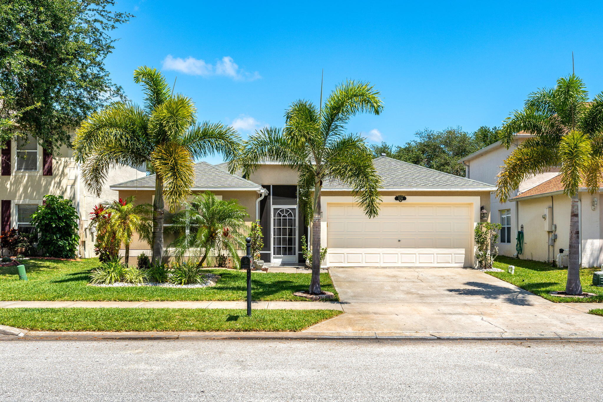 a front view of a house with a yard and palm trees