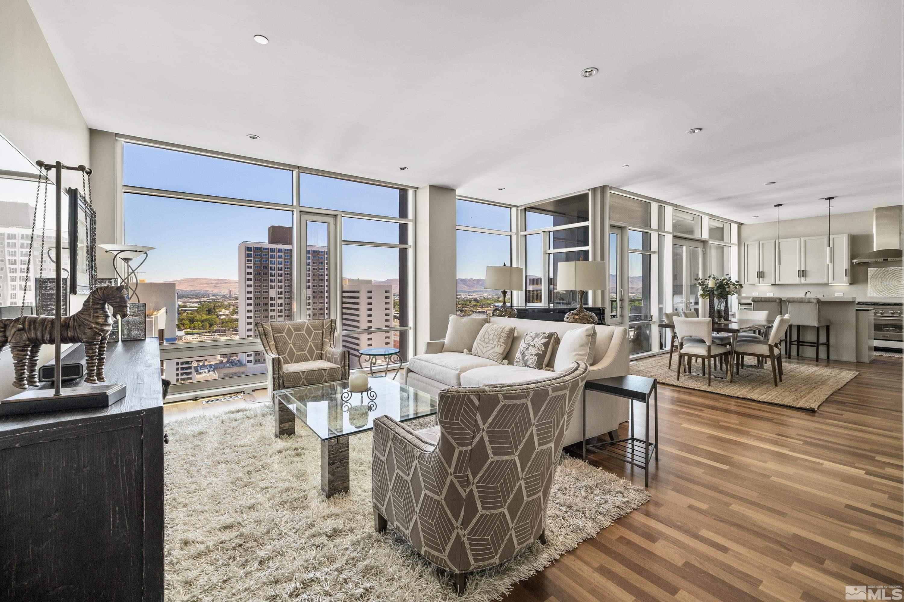 a living room with furniture large window and wooden floor