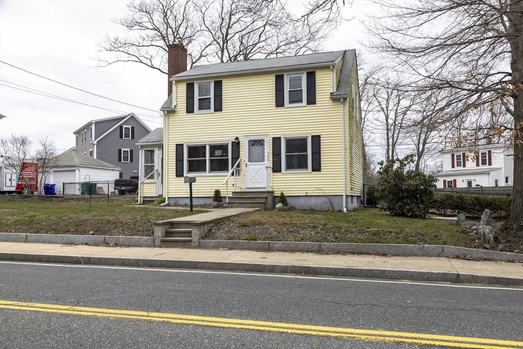 a view of a white house next to a yard and road