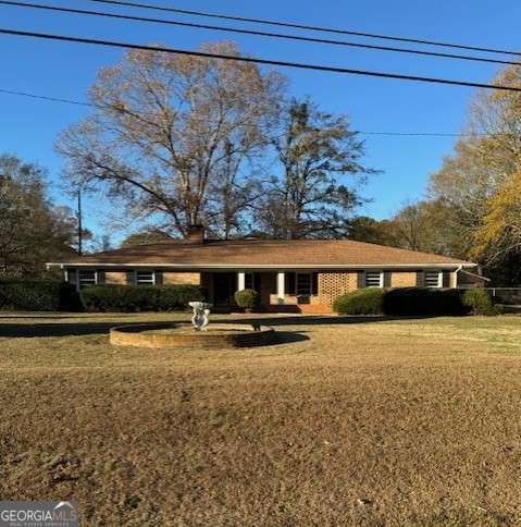 a front view of house with yard and trees in the background