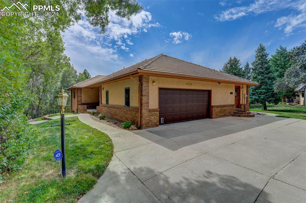 View of property Stucco Exterior featuring a huge driveway and an oversized garage