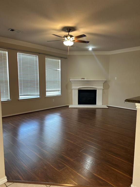 an empty room with wooden floor fireplace and windows