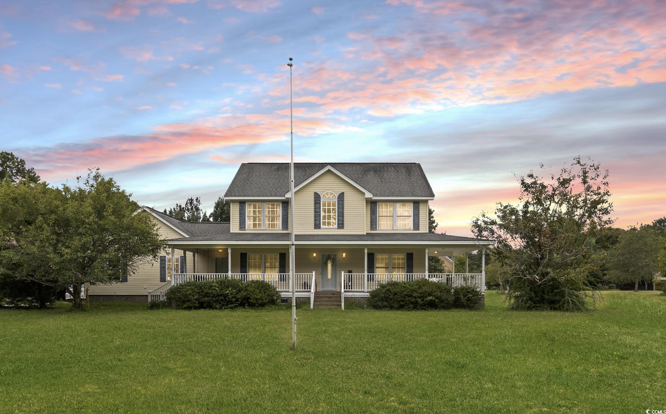 Farmhouse-style home with a lawn and a porch