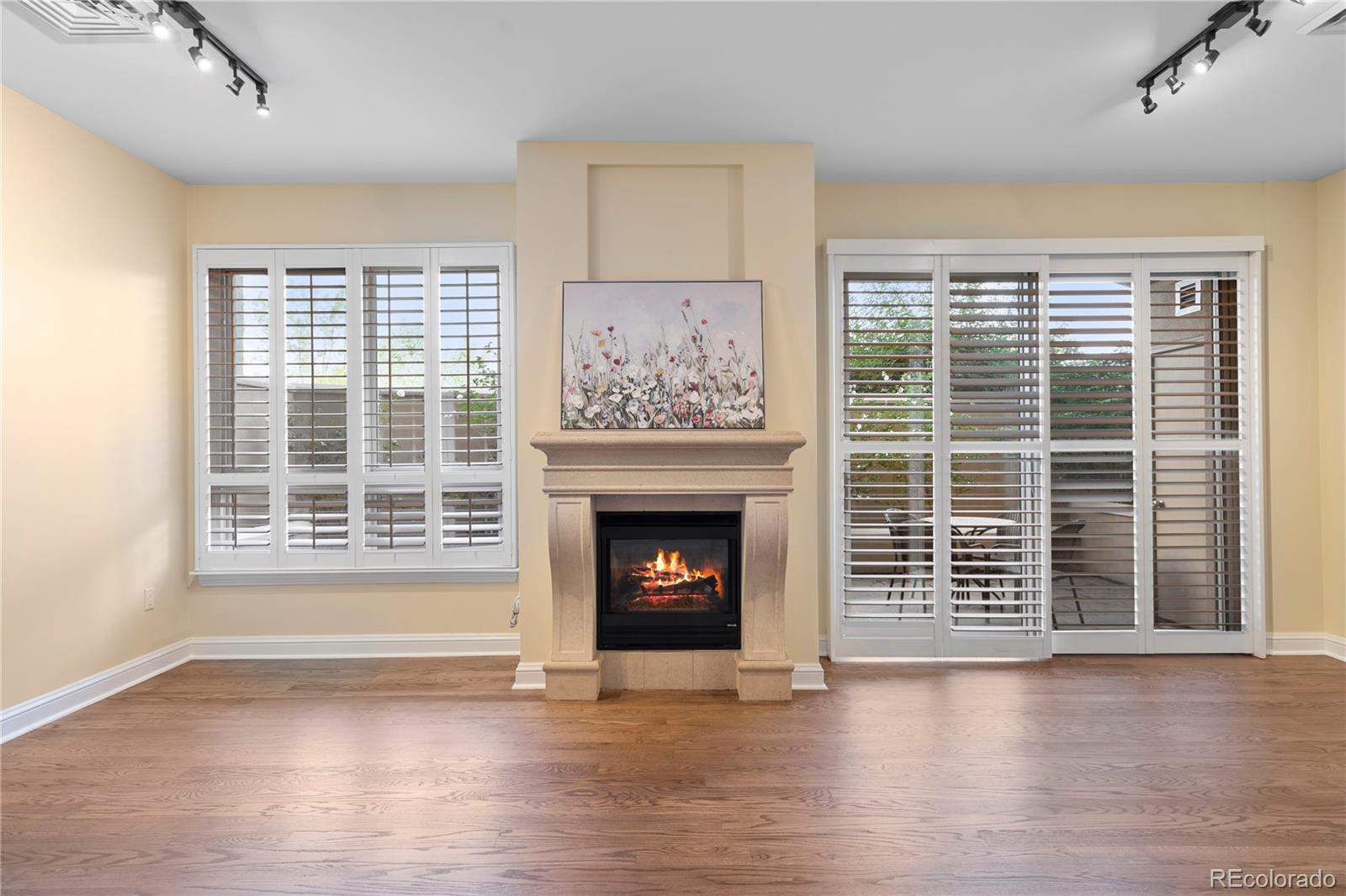 a view of an empty room with wooden floor fireplace and a window